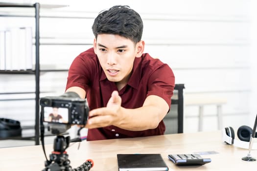 Young asian male blogger setting up camera for recording live vlog video tutorial session at home. IT blogging or vlogging, social media hobby broadcasting, or online learning course concept.
