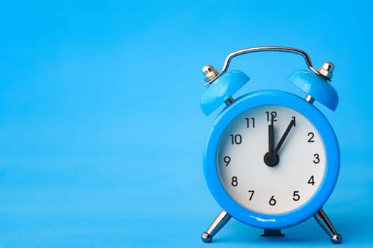 Alarm clock on a blue background, left empty space