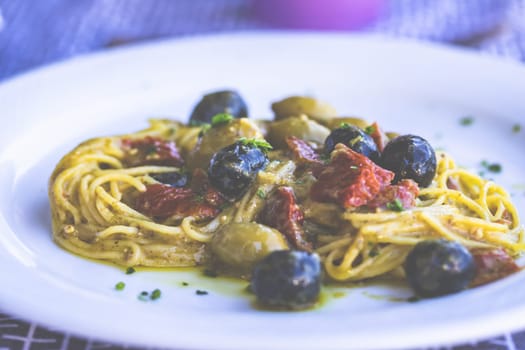 Delicious spaghetti, vegetarian with dried tomatoes, olives and fresh herbs.