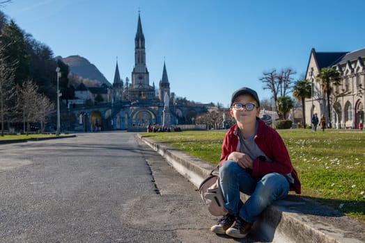 a young boy with the basilica of Lourdes in France