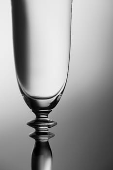 Upper part of a sparkling glass in front of a brightness-running background monochrome