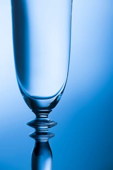 Upper part of a sparkling glass in front of a brightness-running background blue toned.