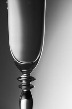 Upper part of a sparkling glass in front of a brightness-running background monochrome
