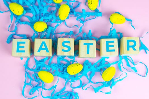Word Easter on wooden cubes and surrounded with multiple egg decorations as a festive Easter background composition.