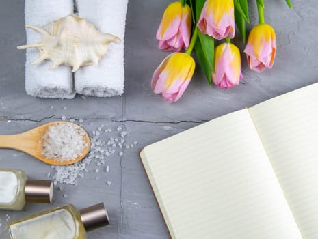 Spa with natural olive soap, tulips and sea salt and an open notebook for writing.