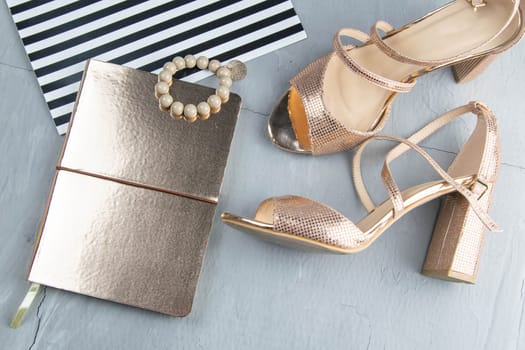 Golden blacknote with bracelet and gold shoes on a concrete background. Flet lay.