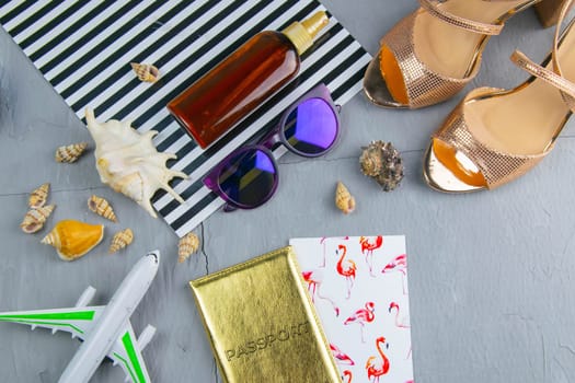 Travel concept. Preparation for the tour: passport, women's shoes, plane, glasses, tanning oil and seashells.