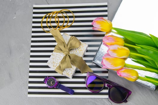Tulips with a gift on a striped background along with glasses and watches.