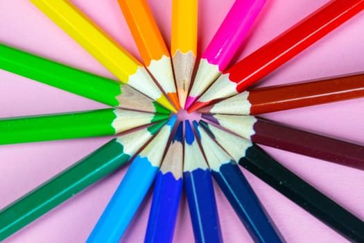 Color pencils on pink pastel background, close up. Set of colorful pencils. Crayons. Top view, flat lay. Back to school, college concept. Abstract background.
