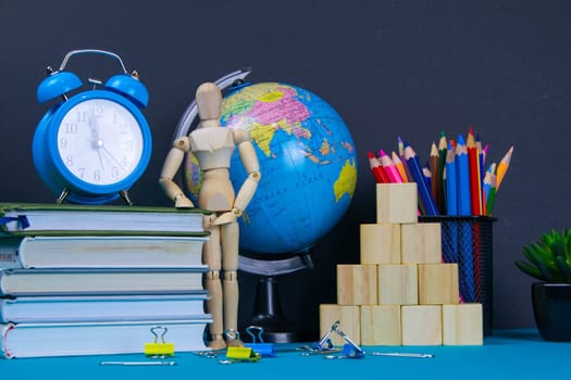 The globe and the clock stand on a stack of books, next to a glass of pencils and the pyramid is folded with wooden cubes and the figure of a wooden man.