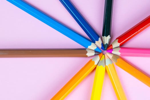 Color pencils on pink pastel background, close up. Set of colorful pencils. Crayons. Top view, flat lay. Back to school, college concept. Abstract background.