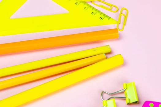 Multi-colored red yellow pinc pencils rulers, pens, pencils and scissors and stationery stand on a pink background.