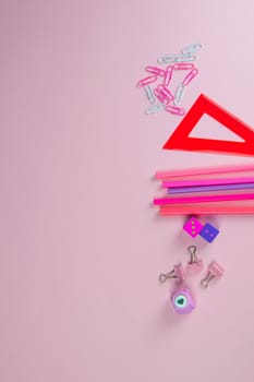 Multi-colored red and pinc pencils rulers, pens, pencils and scissors and stationery stand on a pink background.