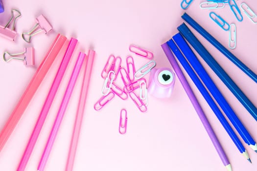 Multi-colored blue and pinc pencils rulers, pens, pencils and scissors and stationery stand on a pink background.
