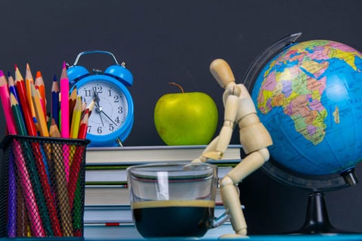 A stack of books with a globe, a glass of pencils, a clock apples and coffee.