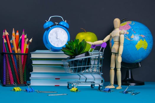 The globe and the clock stand on a stack of books, next to a glass of pencils and the pyramid is folded with wooden cubes and the figure of a wooden man pushes a trolley filled with flower.