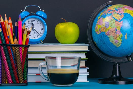 A stack of books with a globe, a glass of pencils, a clock apples and coffee.