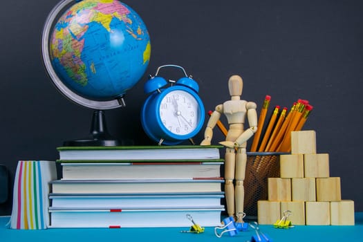 The globe and the clock stand on a stack of books, next to a glass of pencils and the pyramid is folded with wooden cubes and the figure of a wooden man.
