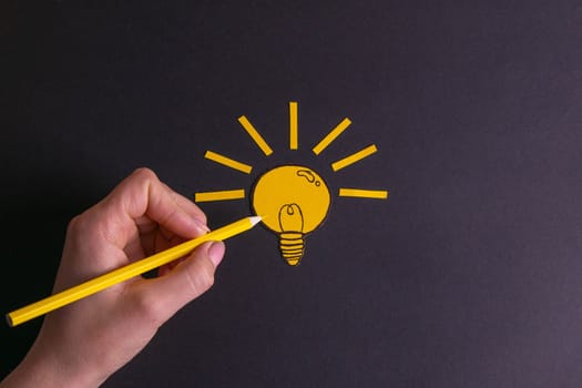 A yellow pencil in hand next to a creative painted light bulb. The concept of innovation and creative ideas/