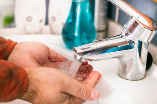 Close view of hands washing with water in the bathroom.