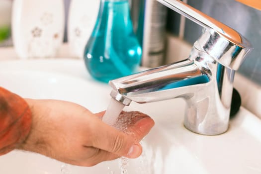 Close view of hands washing with water in the bathroom.
