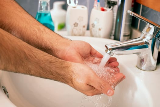 Close view of hands washing with water in the bathroom.