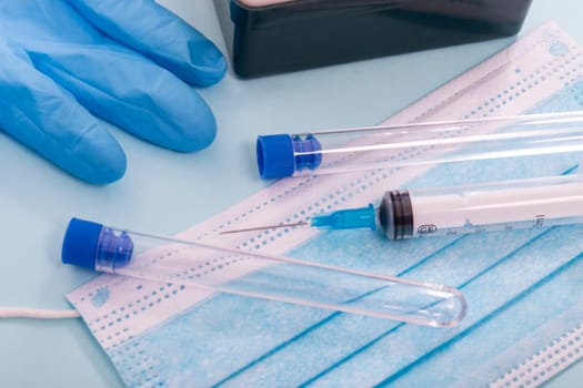 Several laboratory objects including syringe, blue gloves and testing tubes.