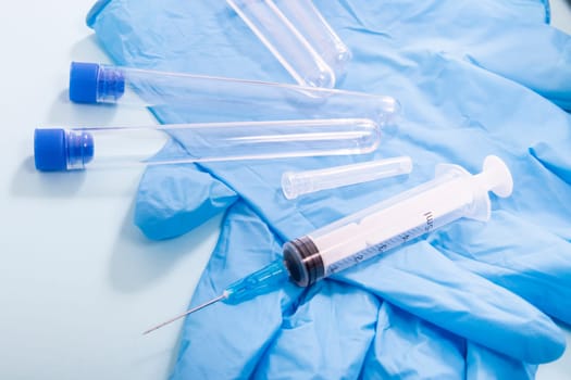 Several laboratory objects including syringe, blue gloves and testing tubes.