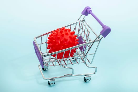 Virus in a miniature shopping cart isolated on a light blue background.