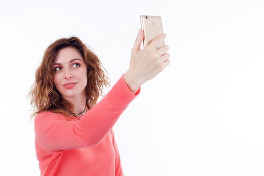 Portrait of cute joyful woman with trendy hairstyle wearing basic t-shirt talking on mobile phone isolated over white background.