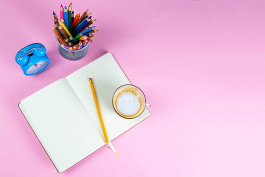 Pencils, note book and clock on the pink table. business conceptual. Top views with clear space