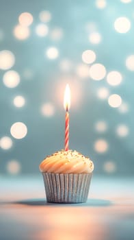 A single birthday cupcake, adorned with a lit candle and gold sprinkles, celebrates a special occasion. The soft lighting and bokeh effect enhance the festive mood.