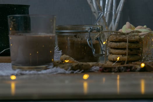 Cocoa with marshmallows and chocolate oven and slices of chocolate stands on a wooden table.