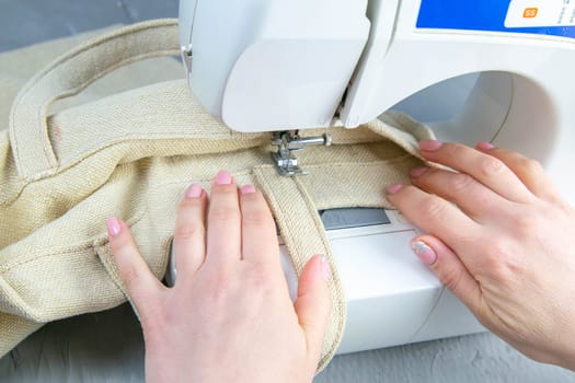 Female hands work on a sewing machine, sewing coffee towel. Close-up.