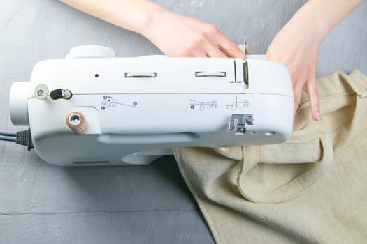 Female hands work on a sewing machine, sewing coffee towel. Close-up.