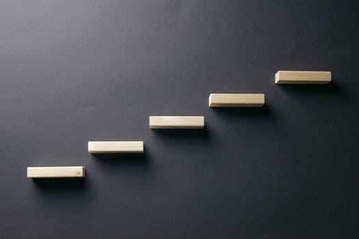 Ladder made with wooden bricks. Concept of personal development, career , changes, success. Black background, copy space for ad.
