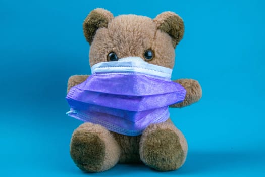 big teddy bear are sitting in blue medical masks on a blue background, concept of protection from respiratory disease, virus, and individual respiratory protection.