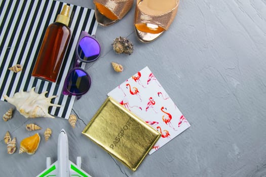 Travel concept. Preparation for the tour: passport, women's shoes, plane, glasses, tanning oil and seashells.