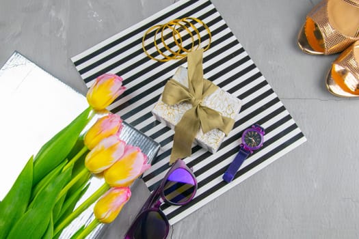 Tulips with a gift on a striped background along with glasses and watches.