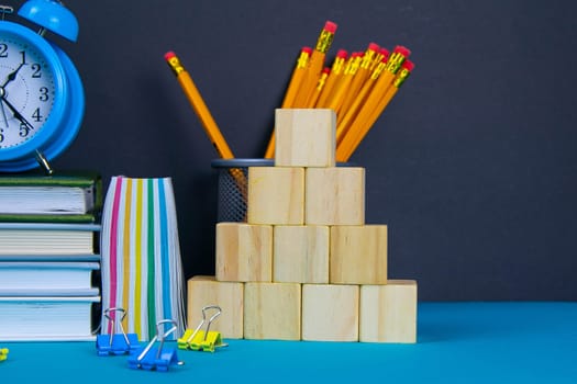 The globe and the clock stand on a stack of books, next to a glass of pencils and the pyramid is folded with wooden cubes.