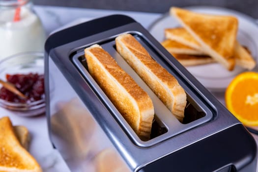 Slices of great toast coming out of the toaster. Healthy breakfast food and heating technology concept.  Focus on slice of great.