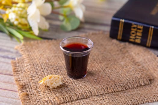 Taking communion concept - the wine and the bread symbols of Jesus Christ blood and body with Holy Bible. Easter Passover and Lord Supper concept Focus on glass.