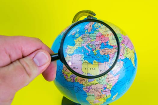Close-up of a hand holding a magnifying glass to look at the globe in the library selective focus Europe.