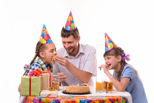 Dad and kids have fun eating cake at the festive table