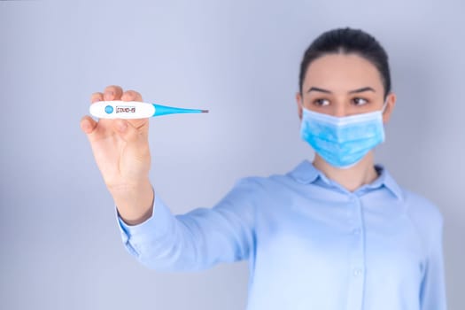 COVID-19 Pandemic Coronavirus Mask Fever Worry Girl Checking Temperature with Thermometer at Home Symptom of SARS-CoV-2. Girl with mask on face check fever one of symptoms of Coronavirus Disease 2019