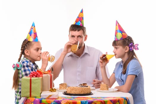 Dad and two daughters drink juice at the festive table