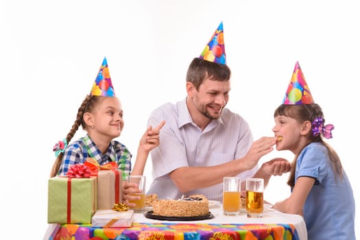 Dad fun stuffing a piece of cake in his daughter's mouth