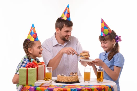 Dad puts his first piece of birthday cake on a plate for his daughter