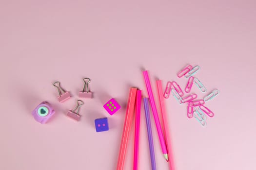 Multi-colored red and pinc pencils rulers, pens, pencils and scissors and stationery stand on a pink background.