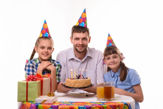 Dad and two daughters with a holiday cake at the table happily look at the frame